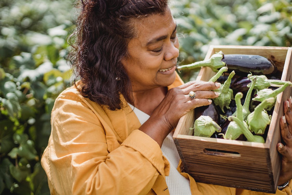 Woman holding box of fresh aubergine